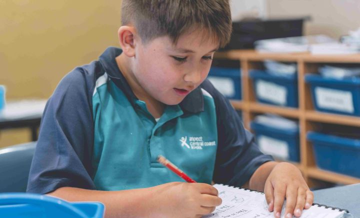 Student focused on writing during classroom learning activity
